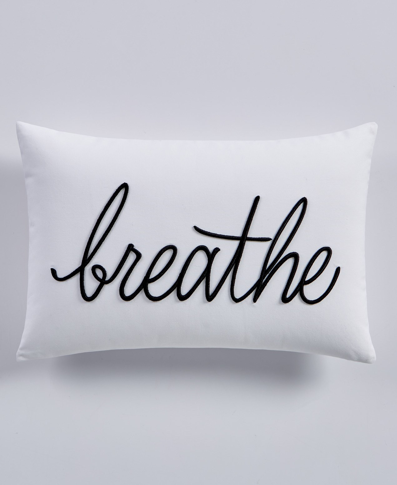Minimalist product shot of a pillow with 'breathe' text
