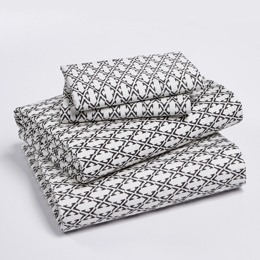 A neatly folded stack of black and white patterned bed sheets