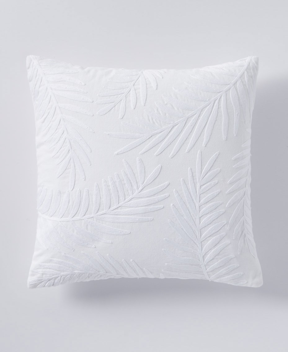 A white pillow with an embroidered white leaf pattern