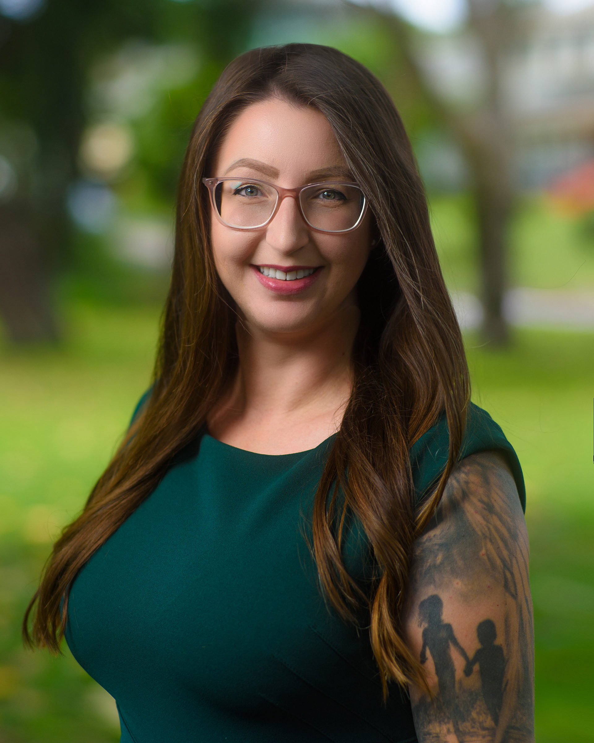 Outdoor portrait of a smiling woman in a green dress, with glasses